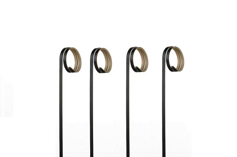 Four black metal stands with gold circular rings on top, lined up on a white background.